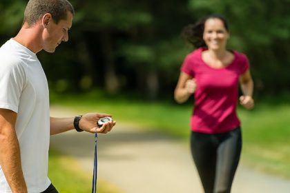 Portrait of male coach timing runner outdoors