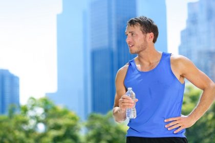 Sport man drinking water bottle in New York City. Male runner sw